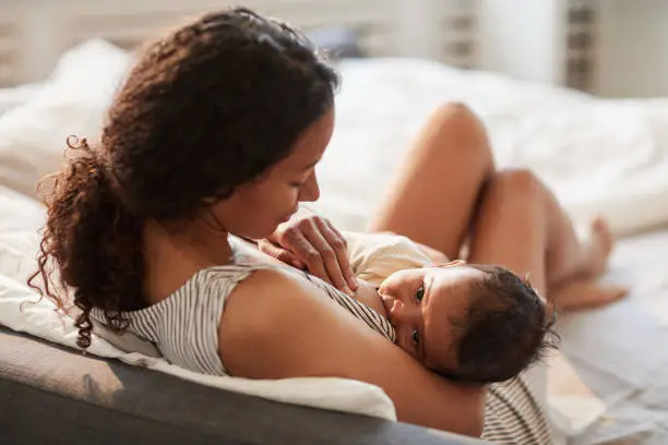 Mother breastfeeding her newborn baby during the early days of postpartum bonding and feeding