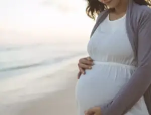 Pregnant woman gently holding her baby bump