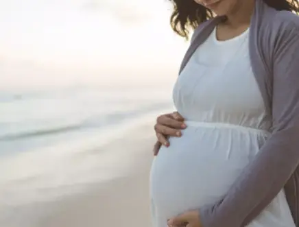 Pregnant woman gently holding her baby bump