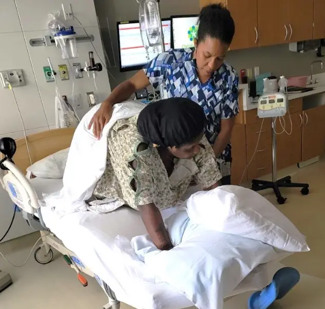 Doula helping a laboring first-time mother change positions during childbirth to promote comfort and labor progress