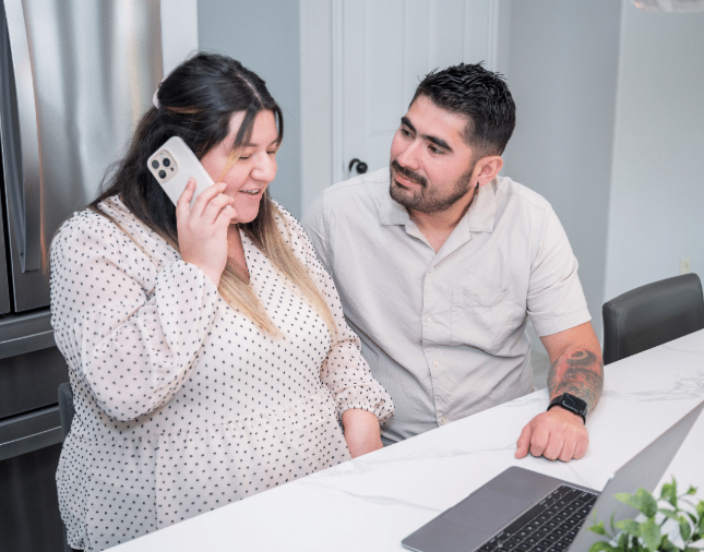 Pregnant couple speaking with a doula by phone while researching birth support options and preparing for the arrival of their baby.