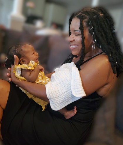 Postpartum doula Nikkita Jervey holding a newborn during an in-home postpartum visit in Delaware.