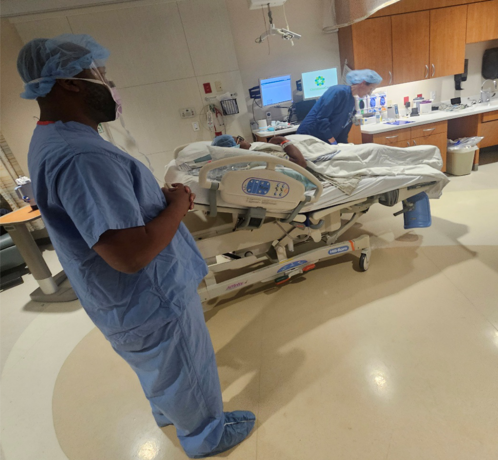 Expectant father standing beside his partner as she is prepared for an unplanned cesarean birth in the hospital