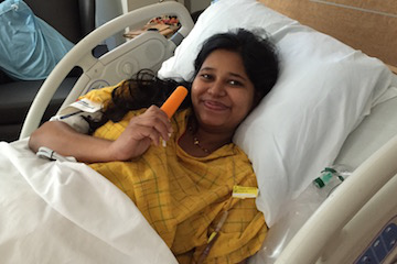 Pregnant woman enjoying a popsicle while resting in a hospital bed during labor